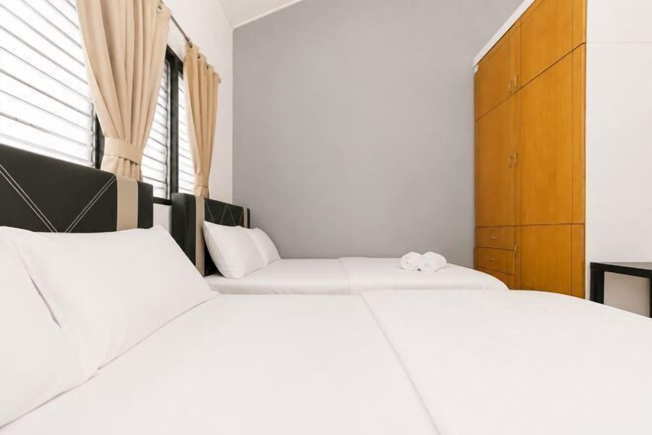 A hotel room with two beds, a wardrobe, and a window with curtains.