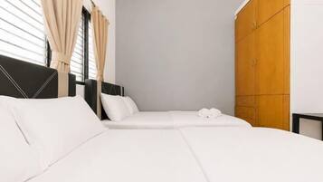 A hotel room with two beds, a wardrobe, and a window with curtains.
