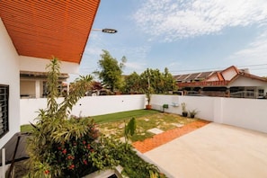 Una casa moderna con techo plano, jardín cuidado y cielo despejado.