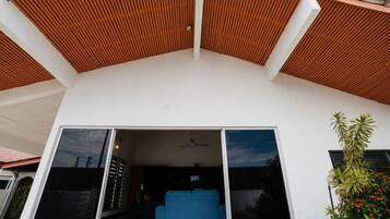 A modern house with a sloped roof, a blue couch, and a large sliding glass door.