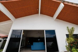 Una casa moderna con techo inclinado, un sofá azul y un amplio ventanal corredera.