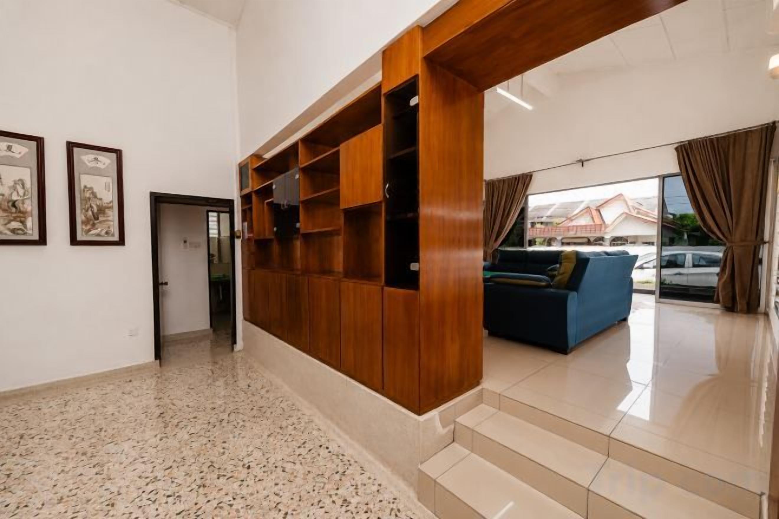 A spacious lobby with a wooden reception desk, a blue sofa, and a staircase leading to upper floors.