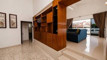 A spacious lobby with a wooden reception desk, a blue sofa, and a staircase leading to upper floors.