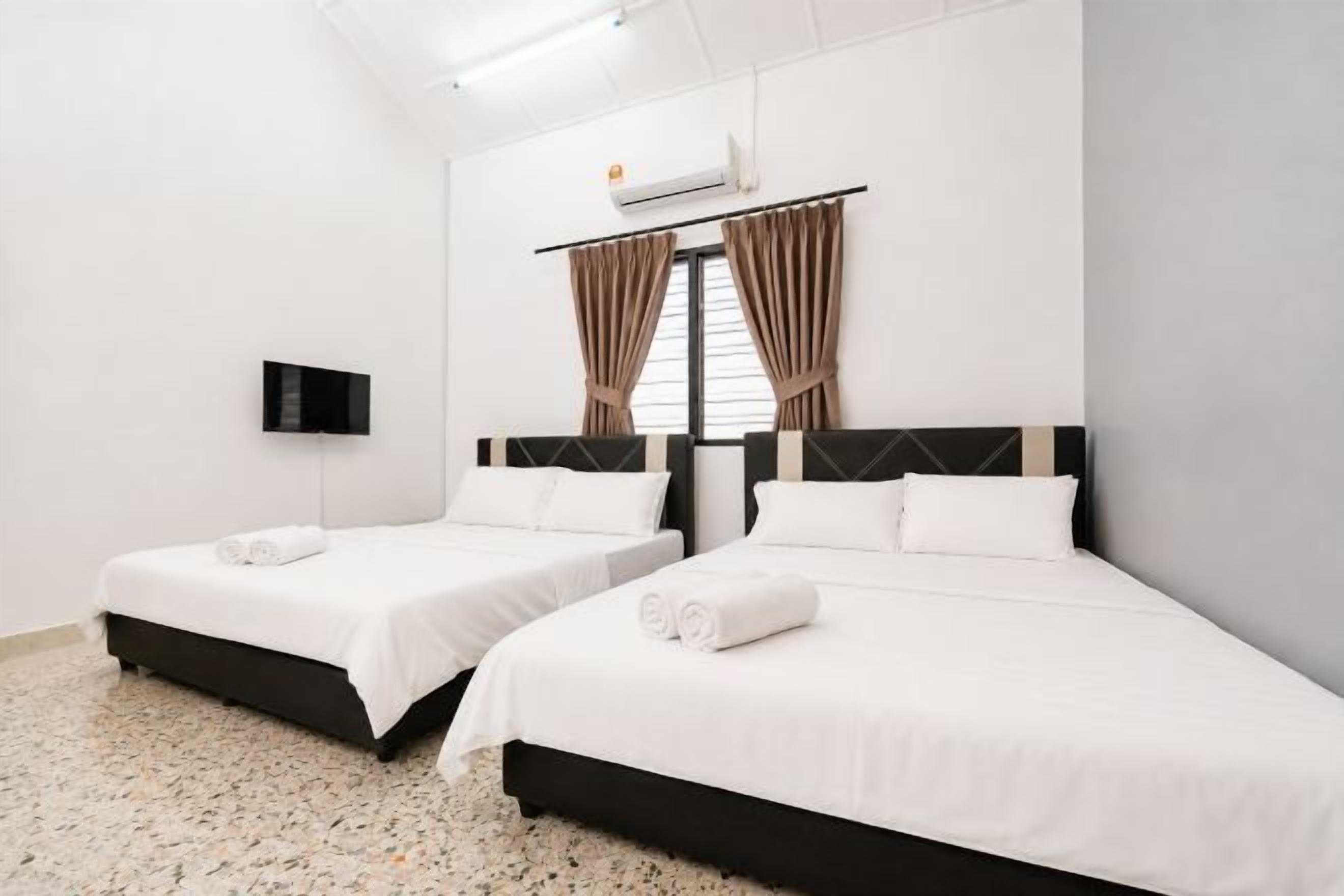 Une chambre d’hôtel avec deux lits, un téléviseur à écran plat et une fenêtre avec des rideaux.
