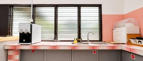 A kitchen with a water dispenser, a sink, and cabinets.
