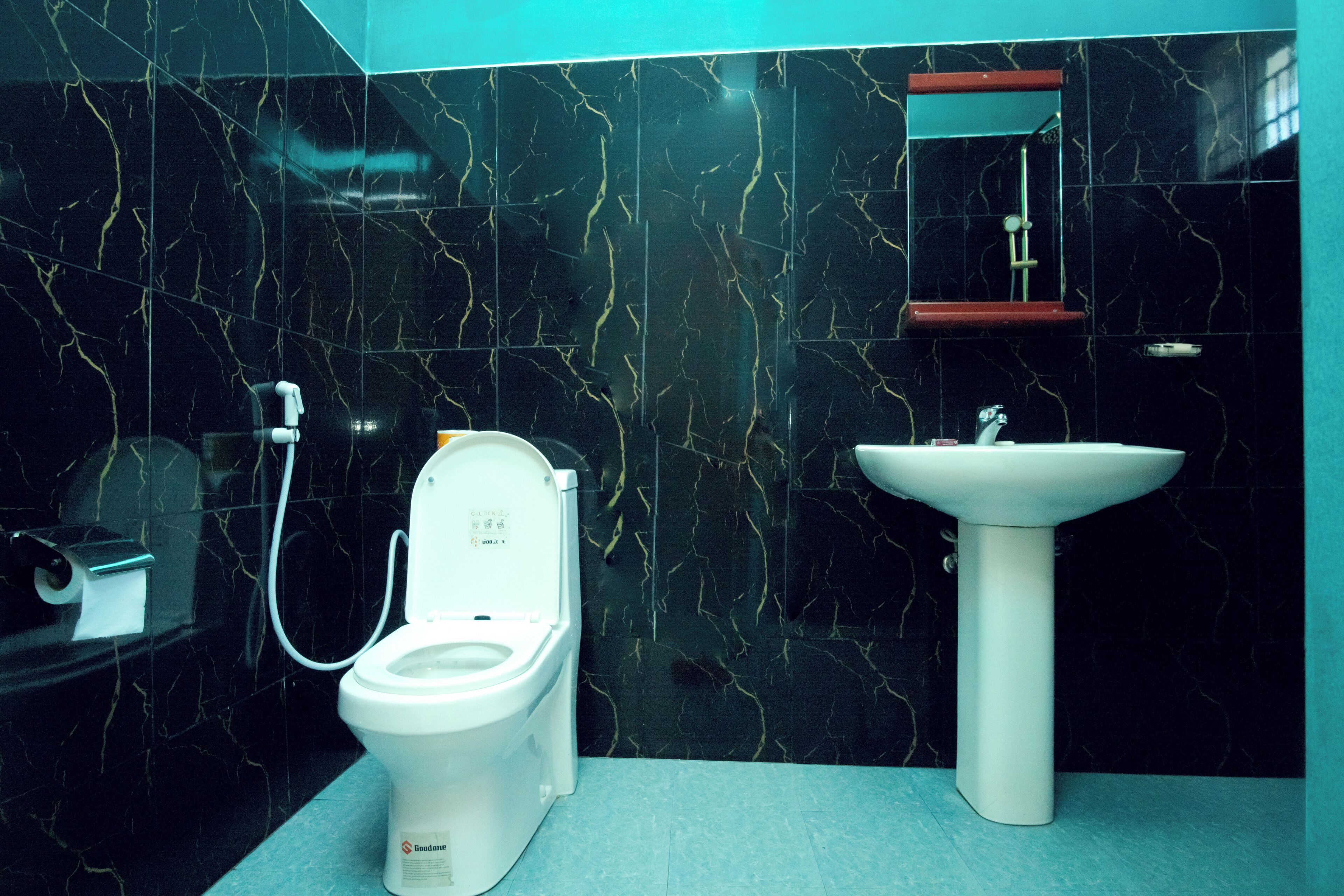 A bathroom with a toilet, sink, and a mirror.