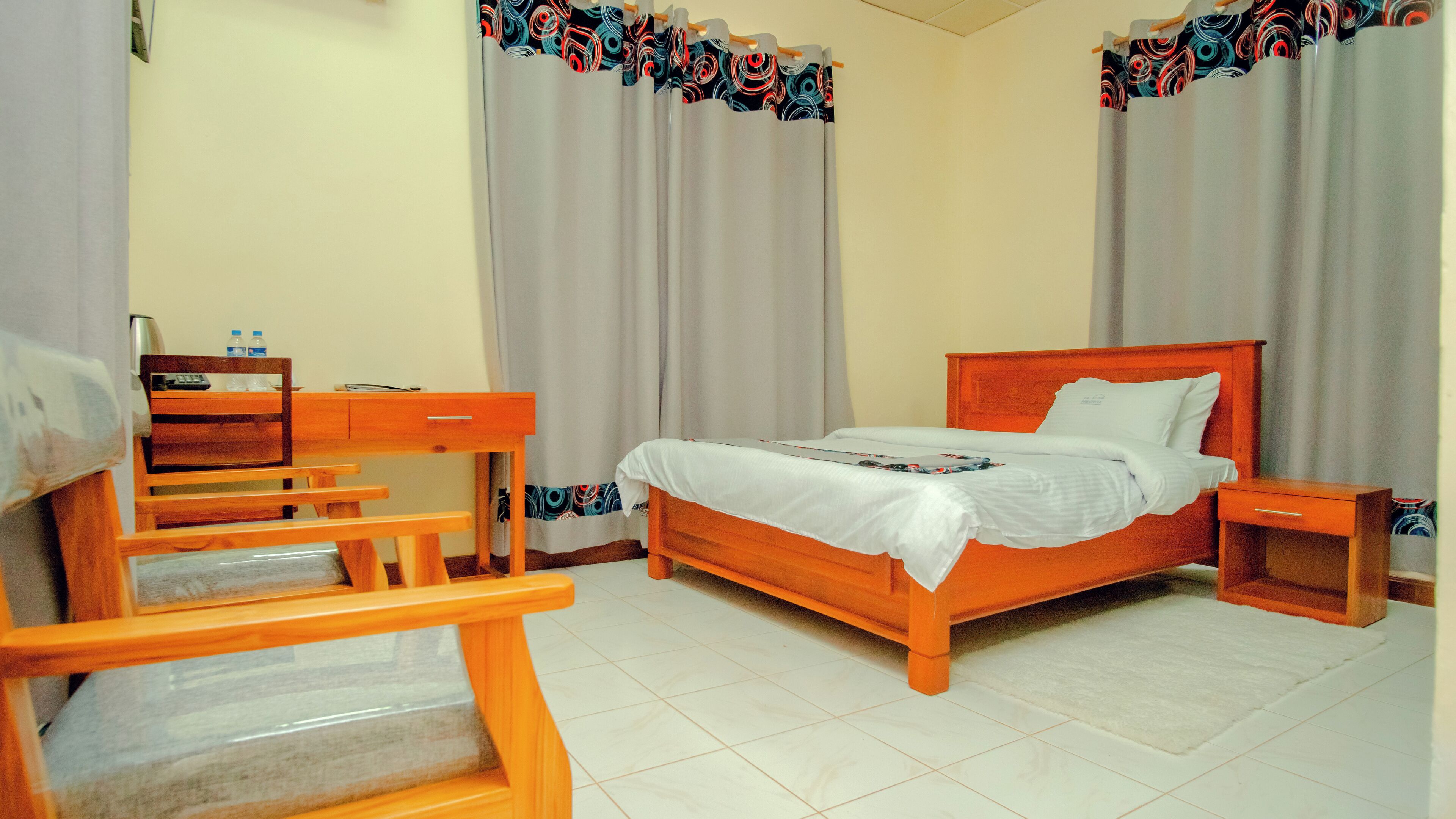 Un dormitorio con una cama y un escritorio de madera, una silla y una mesita de noche.