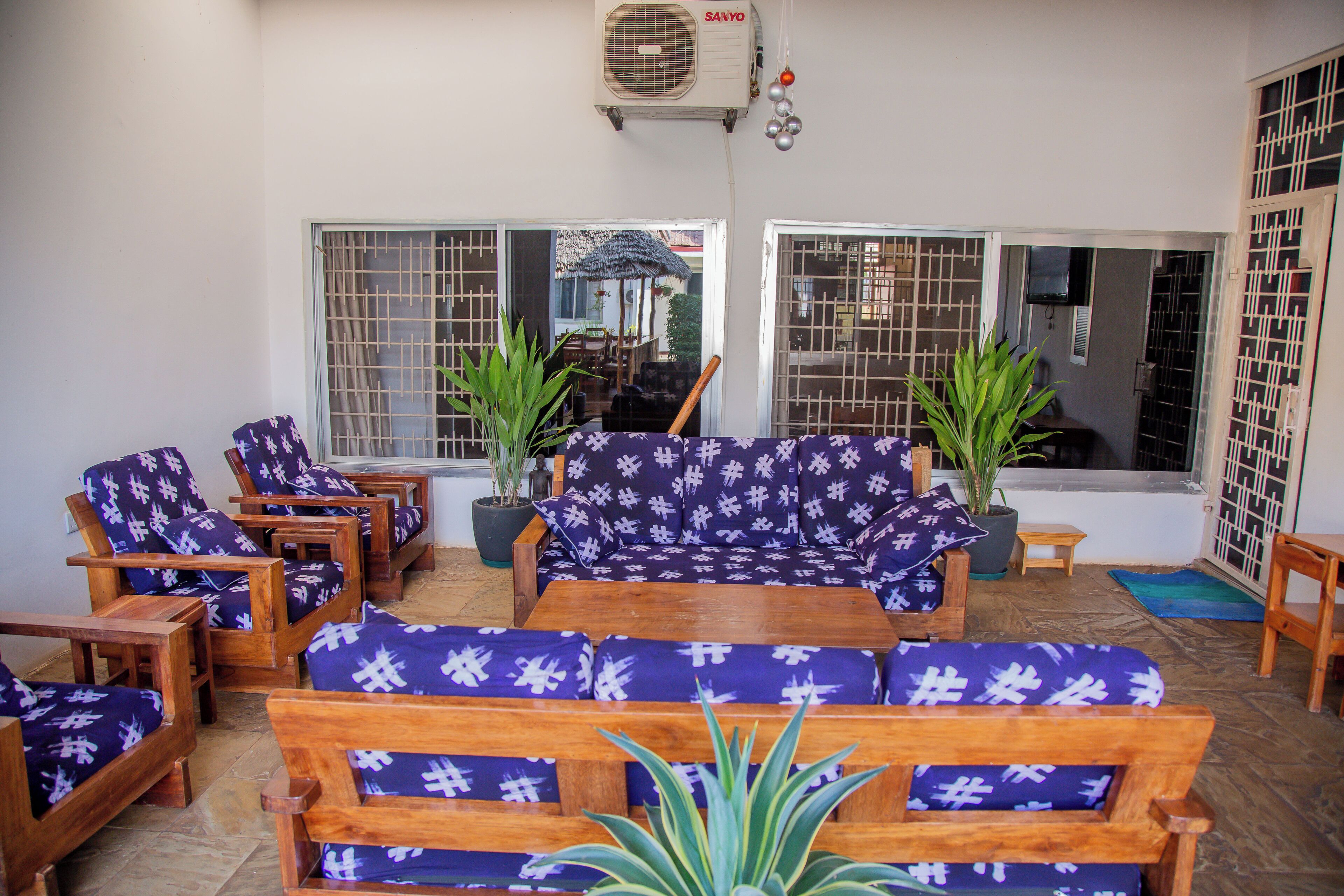 Ein Zimmer mit Holzmöbeln, darunter Sofas und Sessel, sowie Blumentöpfen.