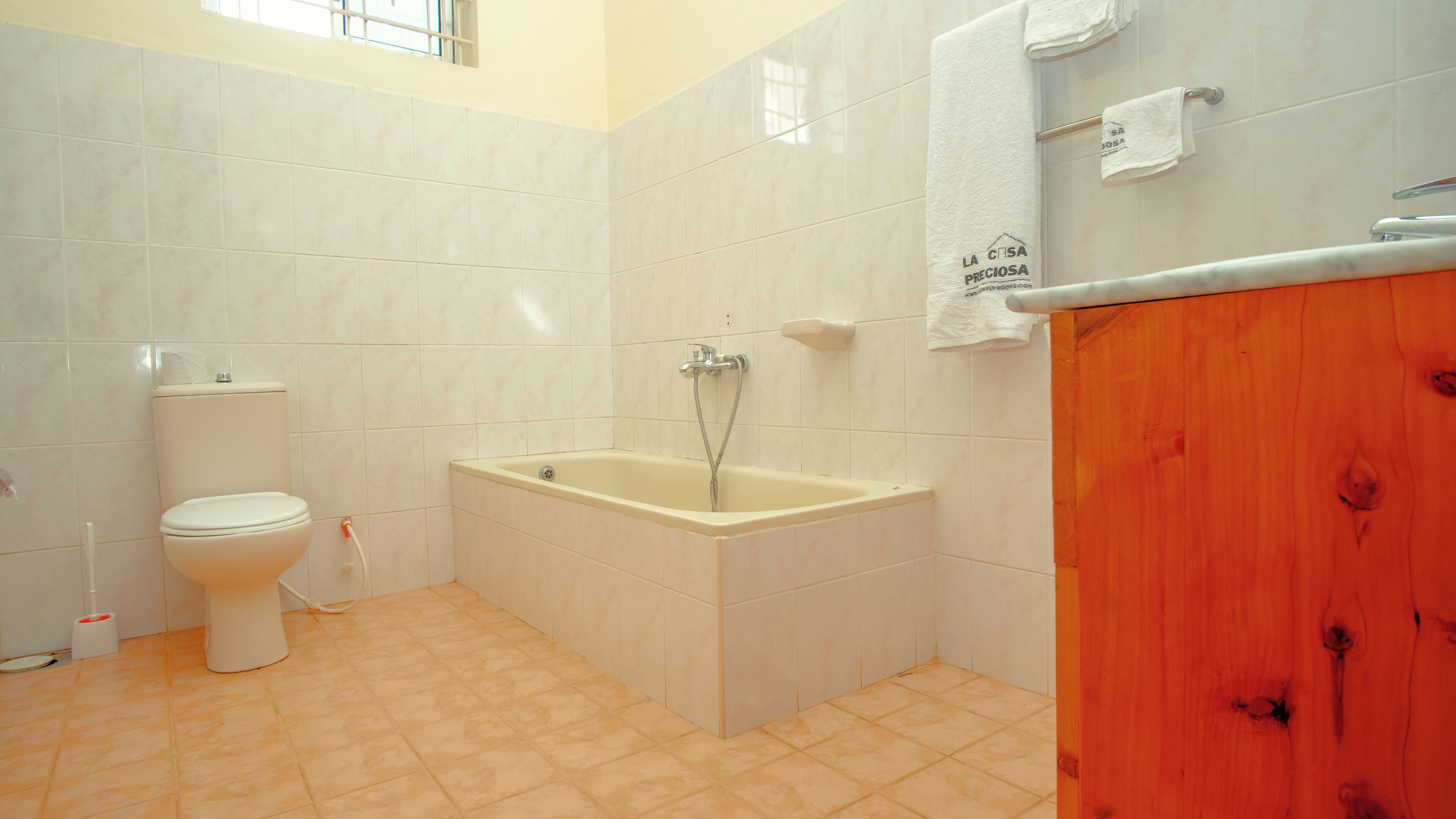 A bathroom with a toilet, bathtub, and wooden vanity.