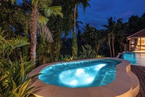 A swimming pool surrounded by tropical vegetation at dusk. - Villa Le Lotus Bleu by BaliSuperHost (Bali)