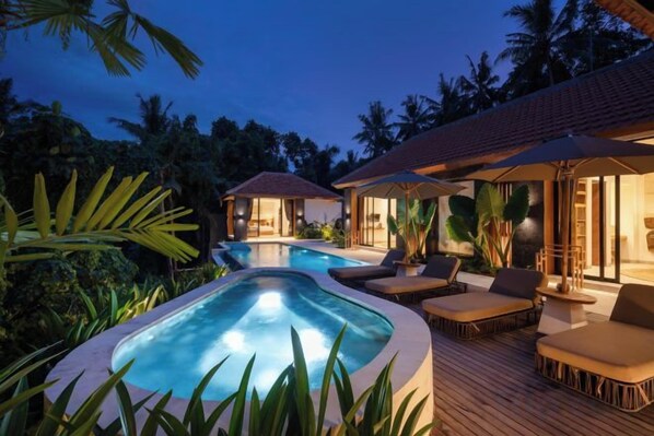 A pool area with lounge chairs and a hot tub, surrounded by tropical vegetation. - Villa Le Lotus Bleu by BaliSuperHost (Bali)