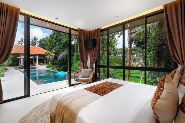 Un dormitorio con una cama grande, vista a una piscina y una silla.