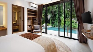 A bedroom with a large bed, a wardrobe, a chair, a TV, and a view of a swimming pool. - Villa Le Lotus Bleu by BaliSuperHost (Bali)