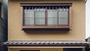 Un edifici amb façana color beix, una finestra amb reixes verticals i un teulat d'uralita.