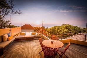 A wooden deck with a round table and chairs, a sofa with cushions, and a railing. - Samastiti Bingin Luxury appartements steps from the beach (Bali)