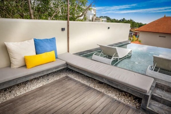 Una terraza en la azotea con zona de estar, piscina y vistas de los edificios circundantes.