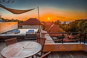 A rooftop terrace with a table and chairs, a hammock, and a view of the sunset. - Samastiti Bingin Luxury appartements steps from the beach (Bali)