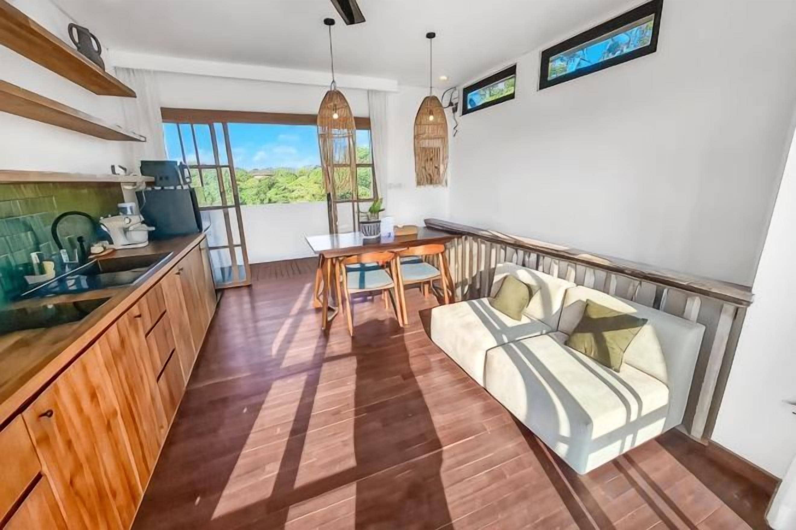 A modern kitchen with wooden cabinets and a dining area with a sofa and table.