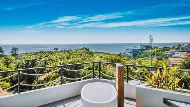 Un balcón con vista al mar, una barandilla y un objeto blanco en el suelo.