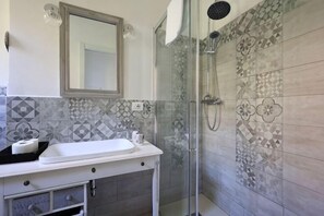 A bathroom with a sink, mirror, shower, and patterned tiles. - Oasis in the Center of Bologna (Bologna)