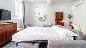 Ein Schlafzimmer mit einem großen Bett, einem Fernseher, einer Holzkommode und einem Schreibtisch mit Stuhl.