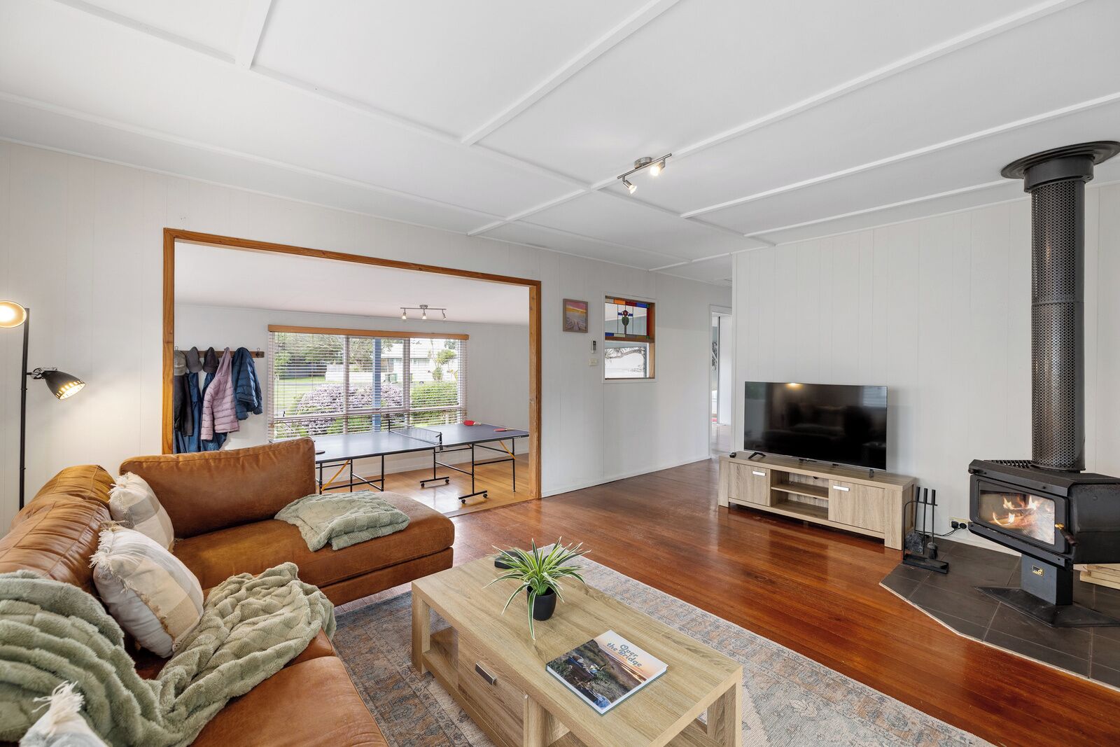 A modern living room with a sofa, coffee table, TV, and a wood-burning stove.