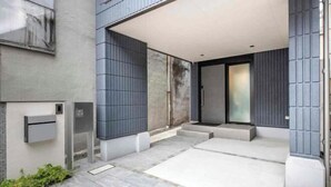 Une entrée moderne avec un patio couvert, une boîte aux lettres et une porte en verre.