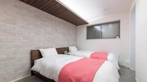 Une chambre avec deux lits, un mur en briques, un plafond en bois et une fenêtre.