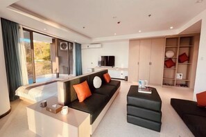 A modern living room with a sofa, ottoman, and a flat-screen TV.