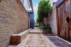 Un estrecho sendero con un muro de piedra a un lado y una puerta de madera al otro, que conduce a un edificio.