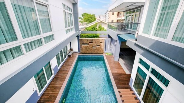 Un hôtel moderne doté d’une piscine centrale, de nombreux balcons et offrant une vue sur les environs.