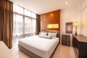 Een moderne hotelkamer met een groot bed, een nachtkastje, een lamp en een wandlamp.