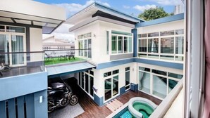 Un immeuble moderne à plusieurs étages, doté d’une piscine, de grandes fenêtres et d’un espace extérieur couvert.
