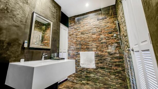 A modern bathroom with a stone wall, a white sink, and a towel hanging on a rack. - Luxury Pure Modern Pool Villa 5Bed Nr BTSCentral (Bangkok)
