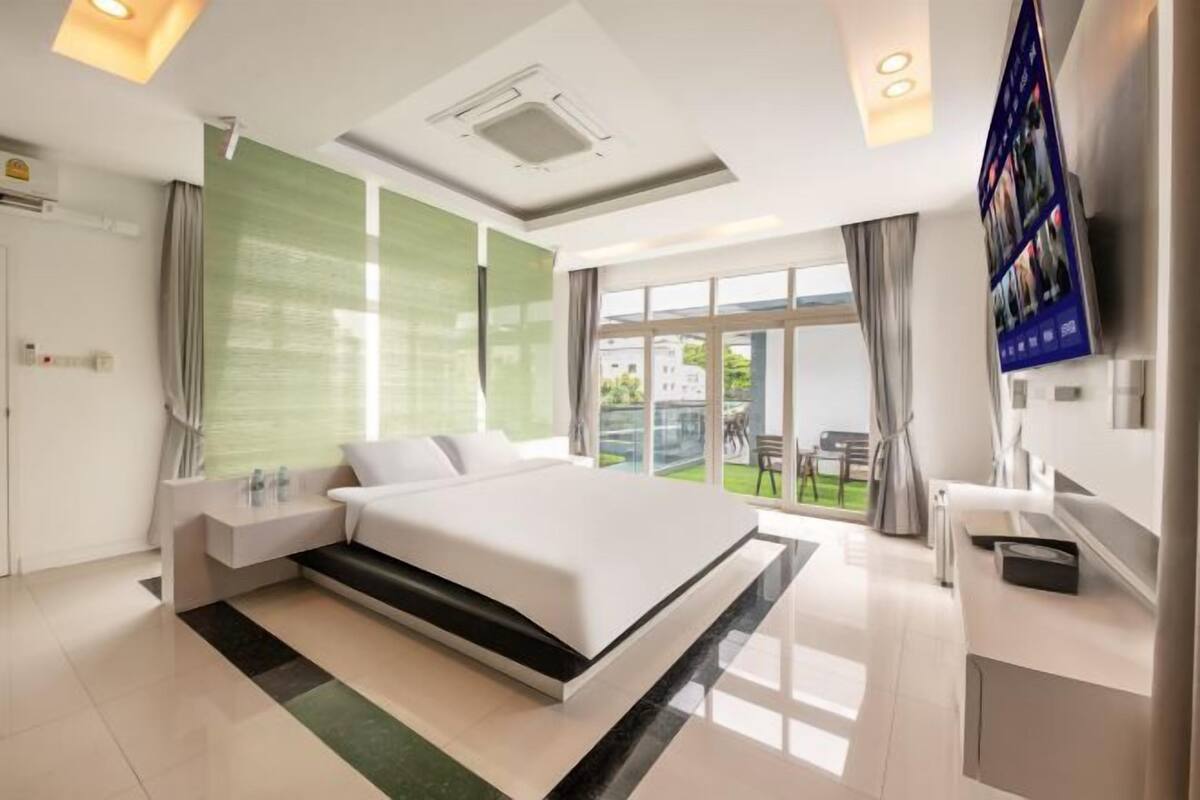 Habitación de hotel moderna con una cama grande, televisor, balcón y baño.