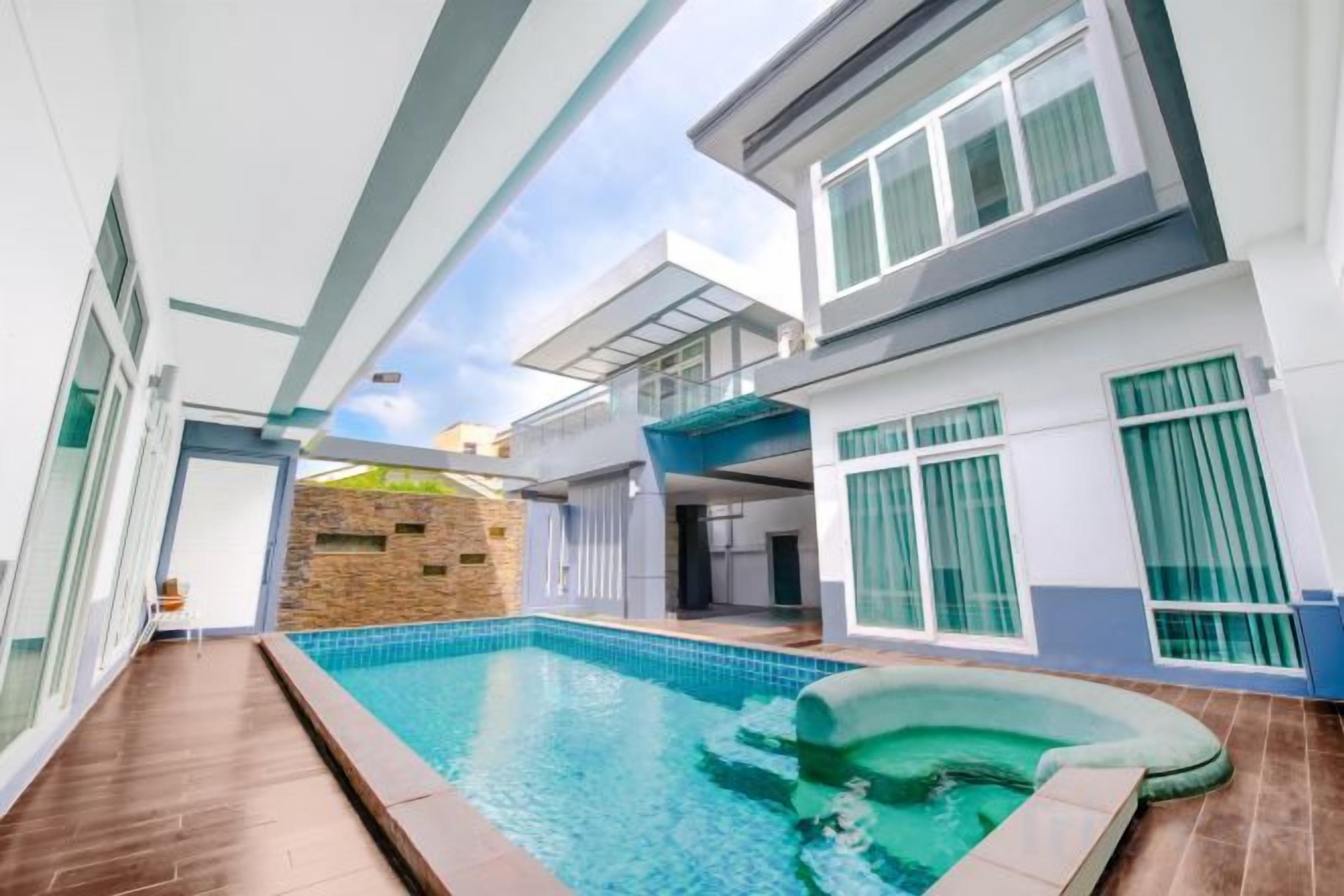 A modern house with a swimming pool, a hot tub, and a covered patio area.