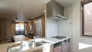A modern kitchen with a central island, a built-in oven, and a dishwasher. - Higashikomagata house (Tokyo)