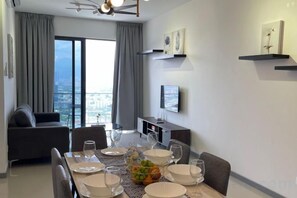 A modern dining area with a table set for four, a sofa, and a city view. - 7Pax Family-Friendly Kepong DesaPark MontKiara (Kuala Lumpur)