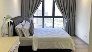 Ein Schlafzimmer mit Bett, Vorhängen, einem Nachttisch und Blick auf Gebäude durch große Fenster.