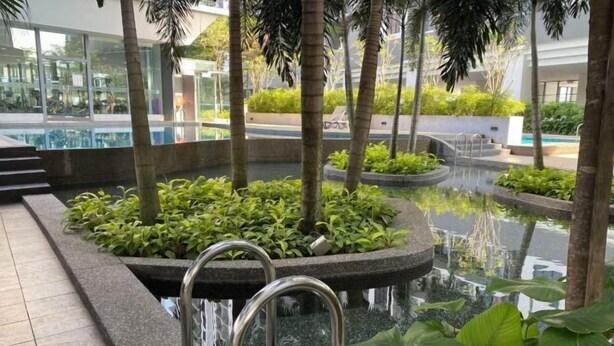 Ein Poolbereich im Innenbereich mit freiem Blick auf die umliegenden Gebäude, eine Treppe, die zum Pool führt, und verschiedene Pflanzen rund um den Pool.