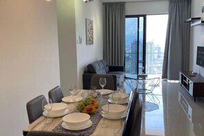 Un coin repas avec une table dressée pour quatre personnes, un canapé et une vue sur la ville.