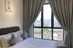 Une chambre d’hôtel avec un grand lit, des rideaux gris et une vue sur la ville.