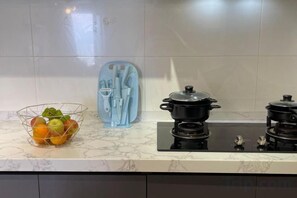A kitchen with a marble countertop, a pot on the stove, and a fruit bowl.