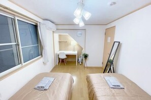 A room with two beds, a desk, a chair, a clock, and a ceiling fan. - nestay villa tokyo takanawa (Tokyo)