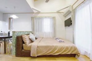 A bedroom with a bed, a desk, and a chair.