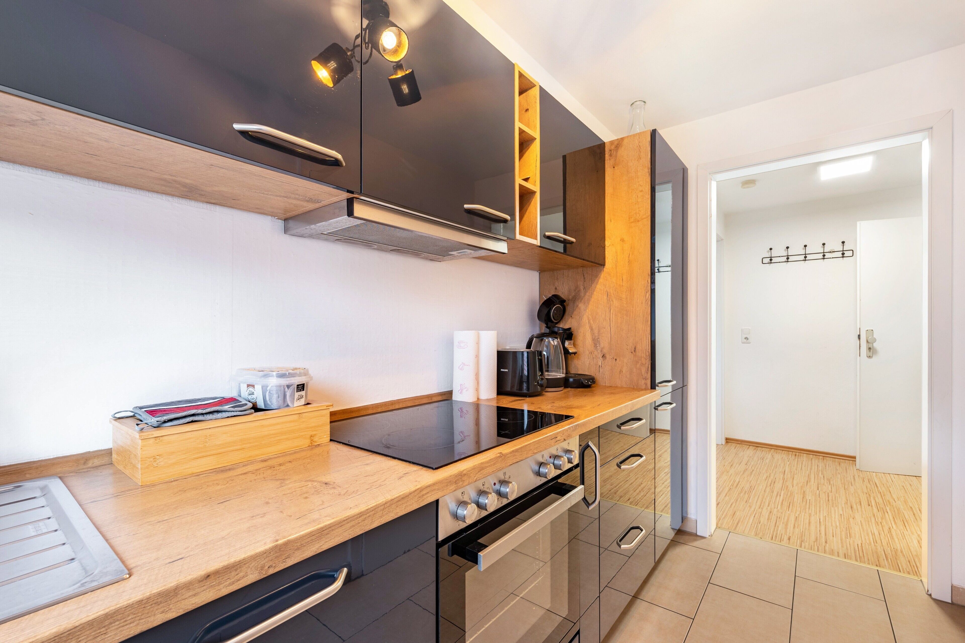 A modern kitchen with a wooden countertop, built-in oven, and a coffee machine.