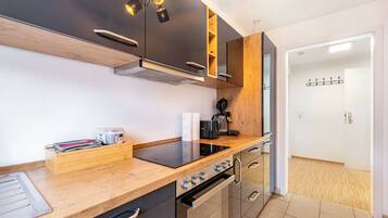 A modern kitchen with a wooden countertop, built-in oven, and a coffee machine.