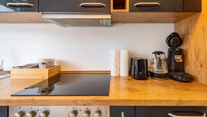 Uma cozinha moderna com fogão por indução preto, bancada de madeira e armários pretos.