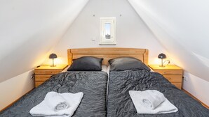Quarto com duas camas, um claraboia, luminárias de cabeceira e uma cabeceira de madeira.