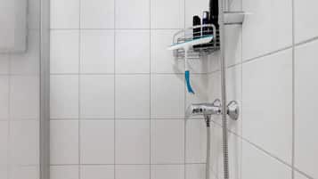 Douchegedeelte met een chroomdouchekop, een handdouche en een metalen plank met toiletartikelen.